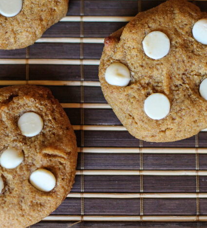 overhead view of white chocolate topped pumpkin cookies on a dark woven mat